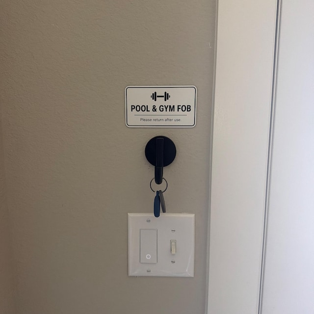 Engraved Pool and Gym Fob sign mounted on a wall above a key hook, from a real customer order